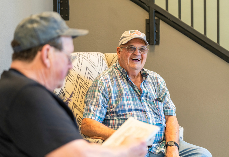 A man sitting in an arm chair laughing.