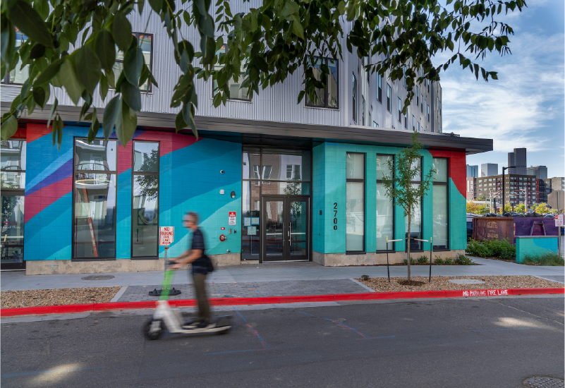 An exterior photo of Nest56 which shows the ground level of the building painted in bright colors.