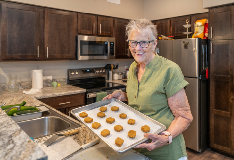 A person holding a sheet of cookies from the oven