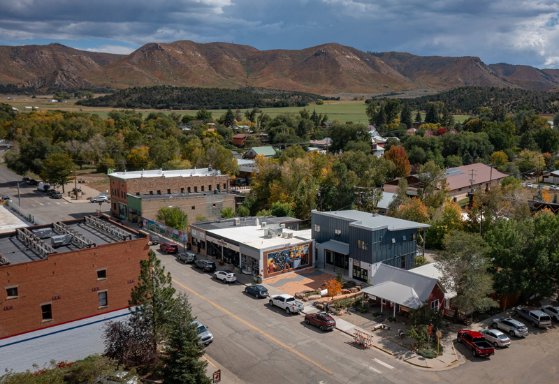 An aerial view of Mancos Commons with a mural wall and orange-leaved tree.