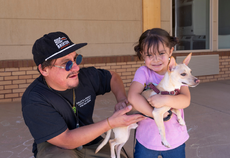 A man and a small girl holding a dog.
