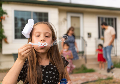A child blowing bubble while the rest of the family is in the background