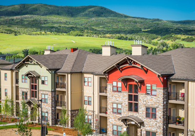 A multifamily building with green hills in the background