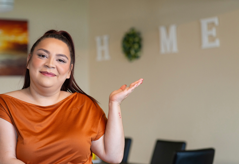 A person sitting in a chair with their hand outstretched to show the letters "HOME" on their wall.