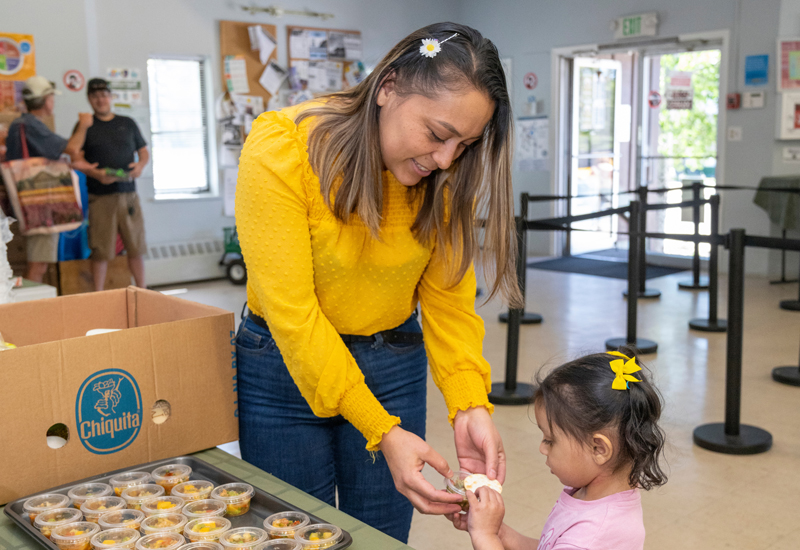 A woman handing a small girl some food at FIRC in Summit County