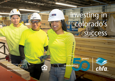 Two men and a woman in hard hats and bright yellow shirts in a factory