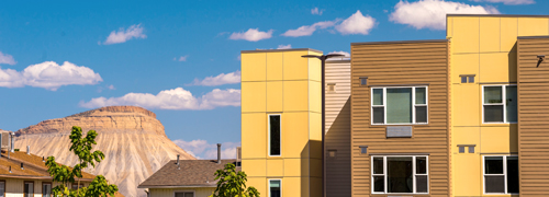 A yellow and tan building next to a large mountain