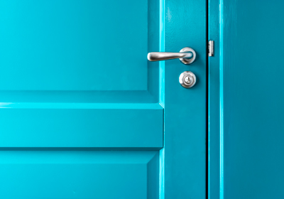 Close up of a teal door with a chrome handle and lock