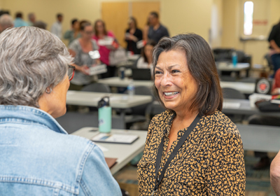 A CHFA staff member speaking to a booth visitor at Housing Colorado 2023