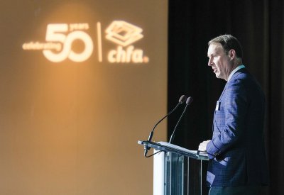 Cris White speaking at a podium with a sign behind him that reads "celebrating 50 years, chfa"