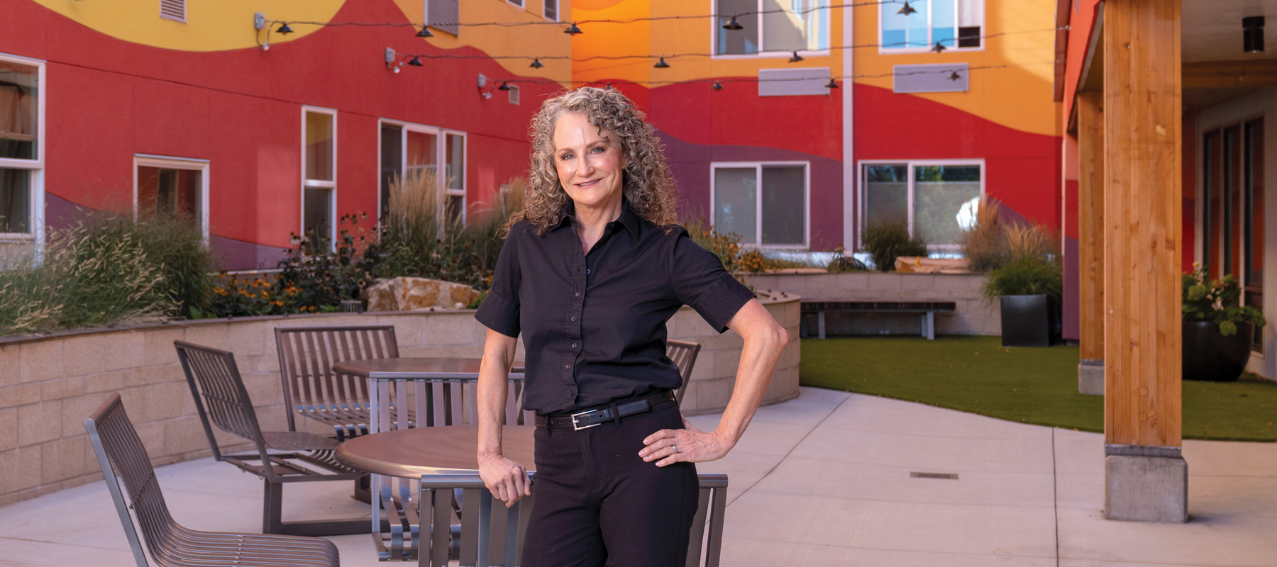 Julie Brewen standing in the courtyard of a colorful red and yellow building