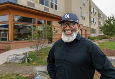 Hassan Latif in a Yankees baseball cap and black shirt smiling