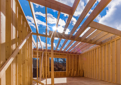 The wooden framing of a room under construction within a building with a view of open sky above.