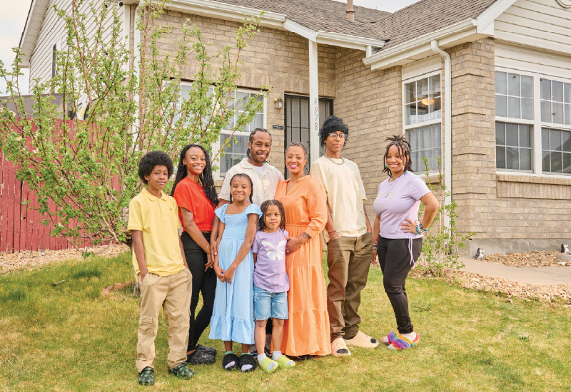 A dressed-up family stands in front of their house.