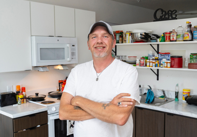 A man standing in a kitchen smiling with his arms crossed