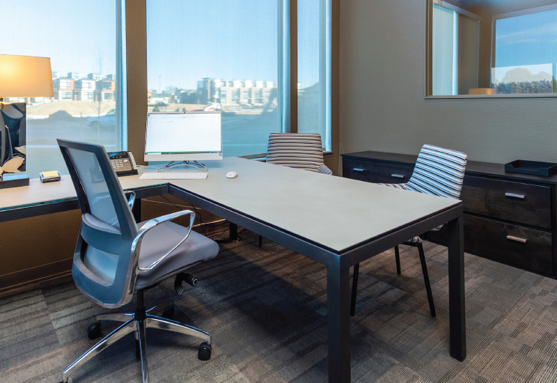 A desk and chairs in a high-rise office with floor to ceiling windows.