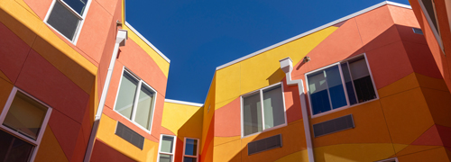 A yellow and coral colored building against a deep blue sky