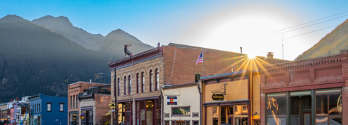 A town's main street with a sun flare behind a building