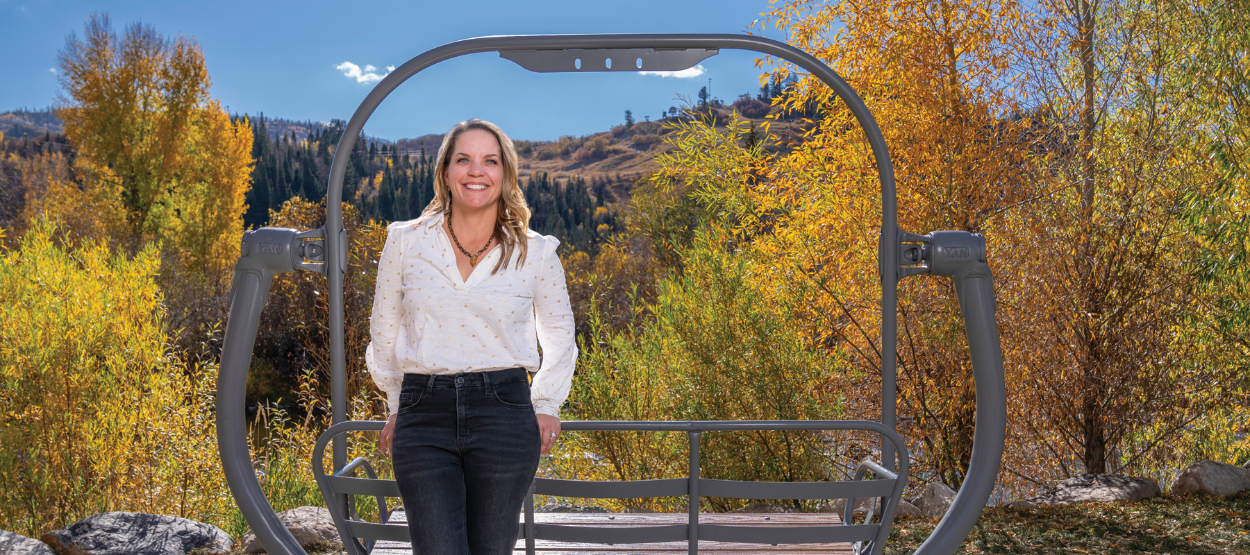Kimball Crangle standing in front of an old ski lift and autumn-leaved trees