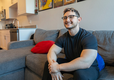 A person sitting on a grey couch smiling