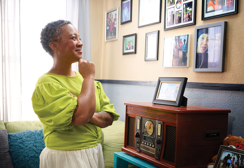 A woman staring at a wall full of framed photos.