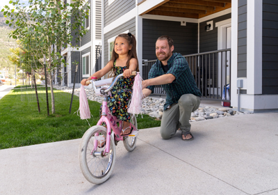 A father holding a bicycle of a little girl at Collegiate Commons