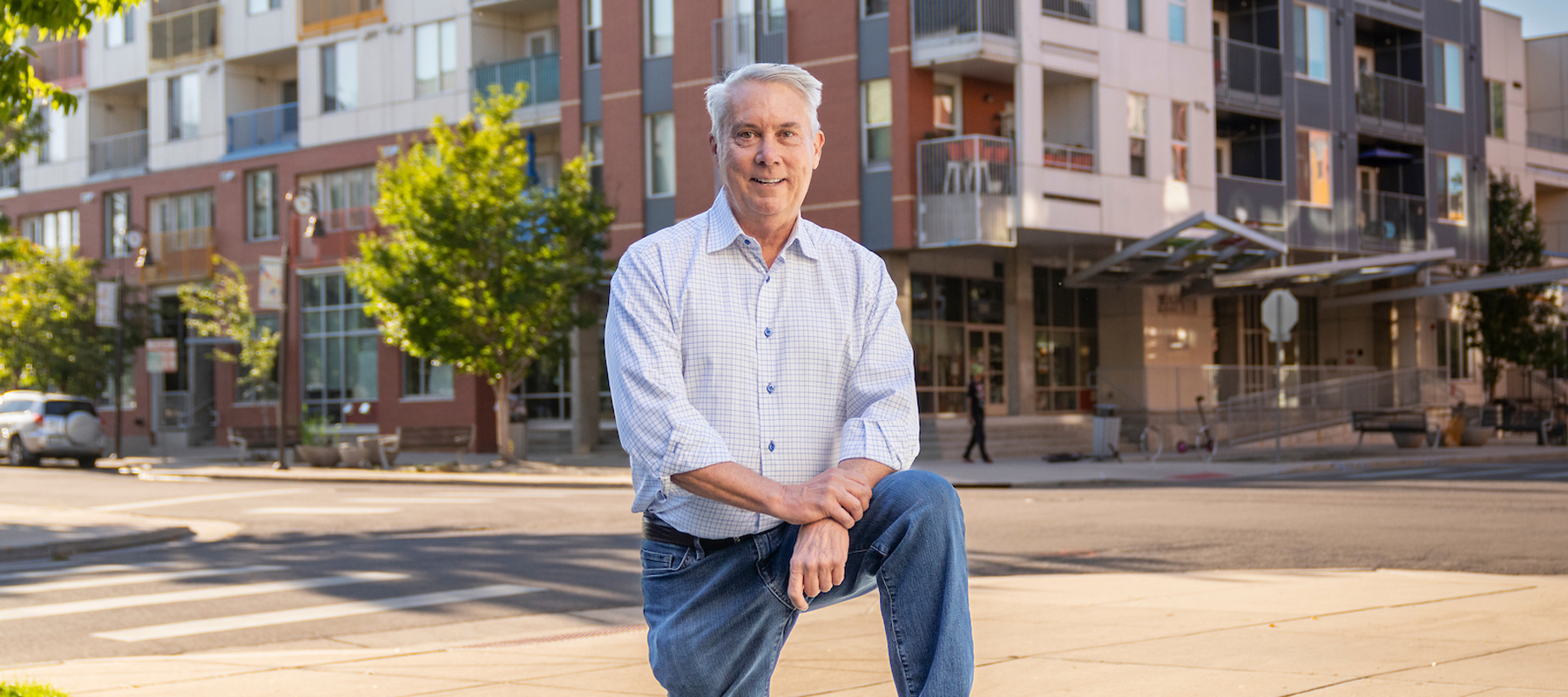 Craig Archibald standing in front of a building with his foot up on a rock.