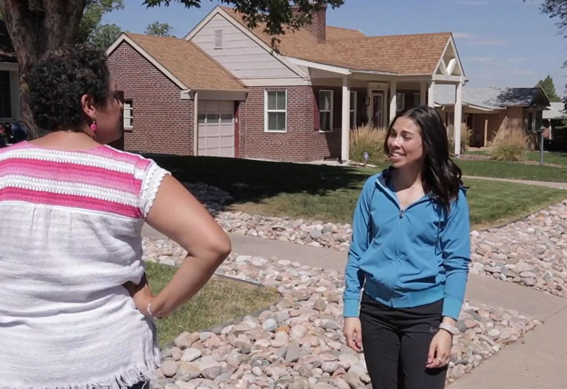 Two ladies meet on a sidewalk outside home