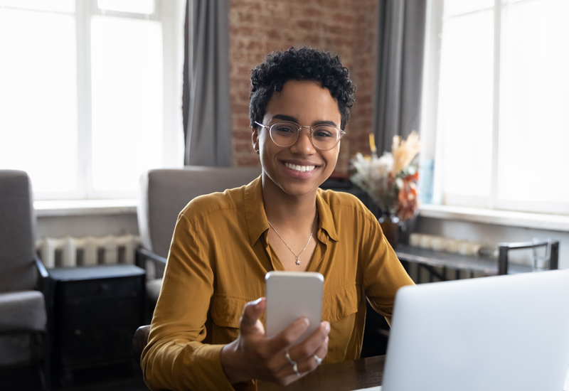 A woman holding a cellphone sitting at a desk