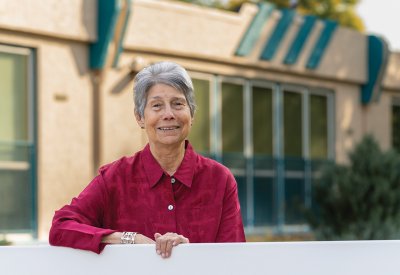 Lucille Echohawk leaning on a fence