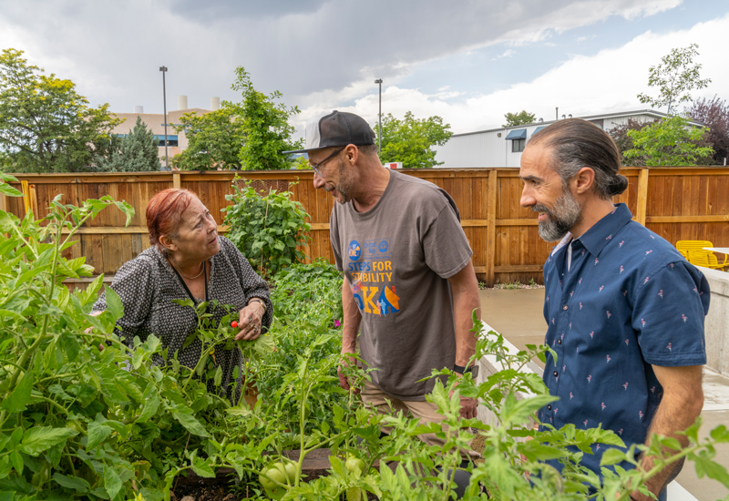 A woman and two men working in the Mason Place community garden.