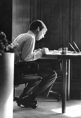 a black and white photo of Jim Roberts writing at a desk