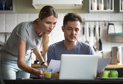 a woman and a man on a laptop in a kitchen