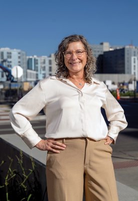 Jennie Rodgers smiling while standing in front of a large building and blue sky