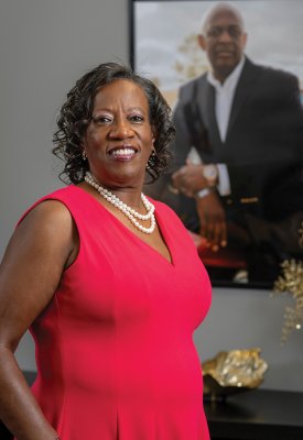 Pastor Kotane Gilbert standing in an office in front of a large photo of a man