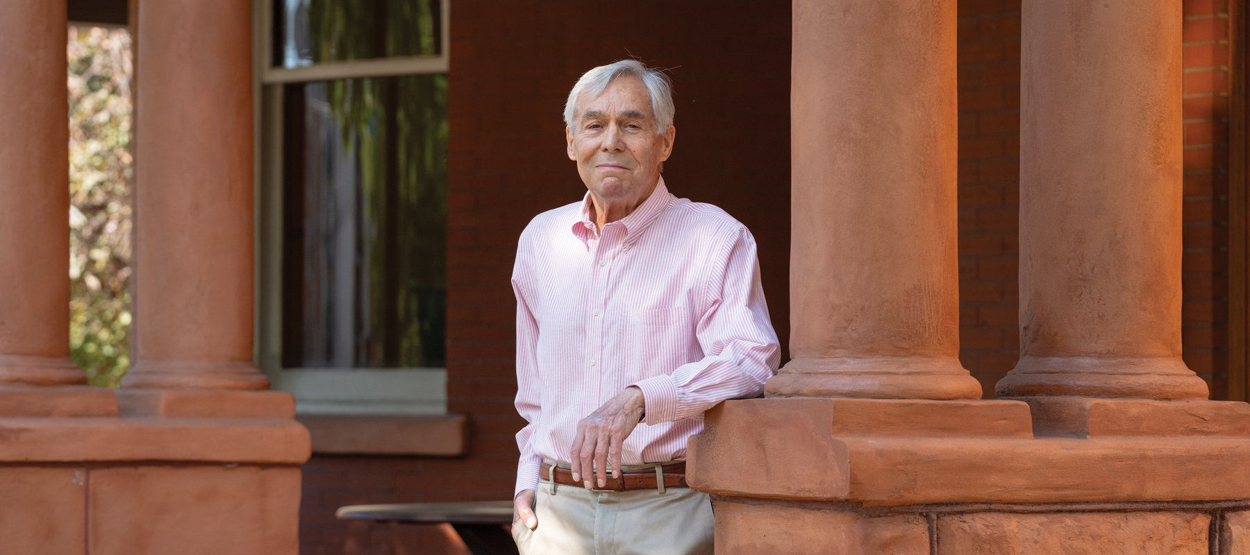 Jim Roberts in a pink shirt leaning on a column