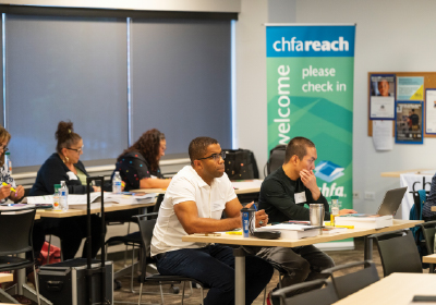 People sitting in a class with a chfareach standing banner.
