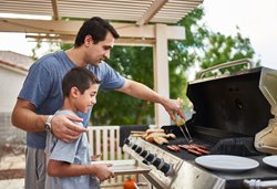 A father and son standing at a barbeque